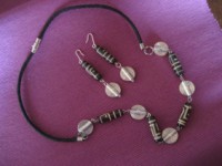 Conjunto de collar y pendientes de cordón con abalorios de hueso y piezas de matel plateado