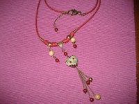 Colgante en cordón rojo con abalorios y pieza central en cristal de bohemia en forma de corazón.