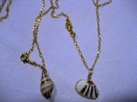 Colgantes de cadena dorados con piezas de cerámica en forma de caracol y concha marina en blanco y dorado